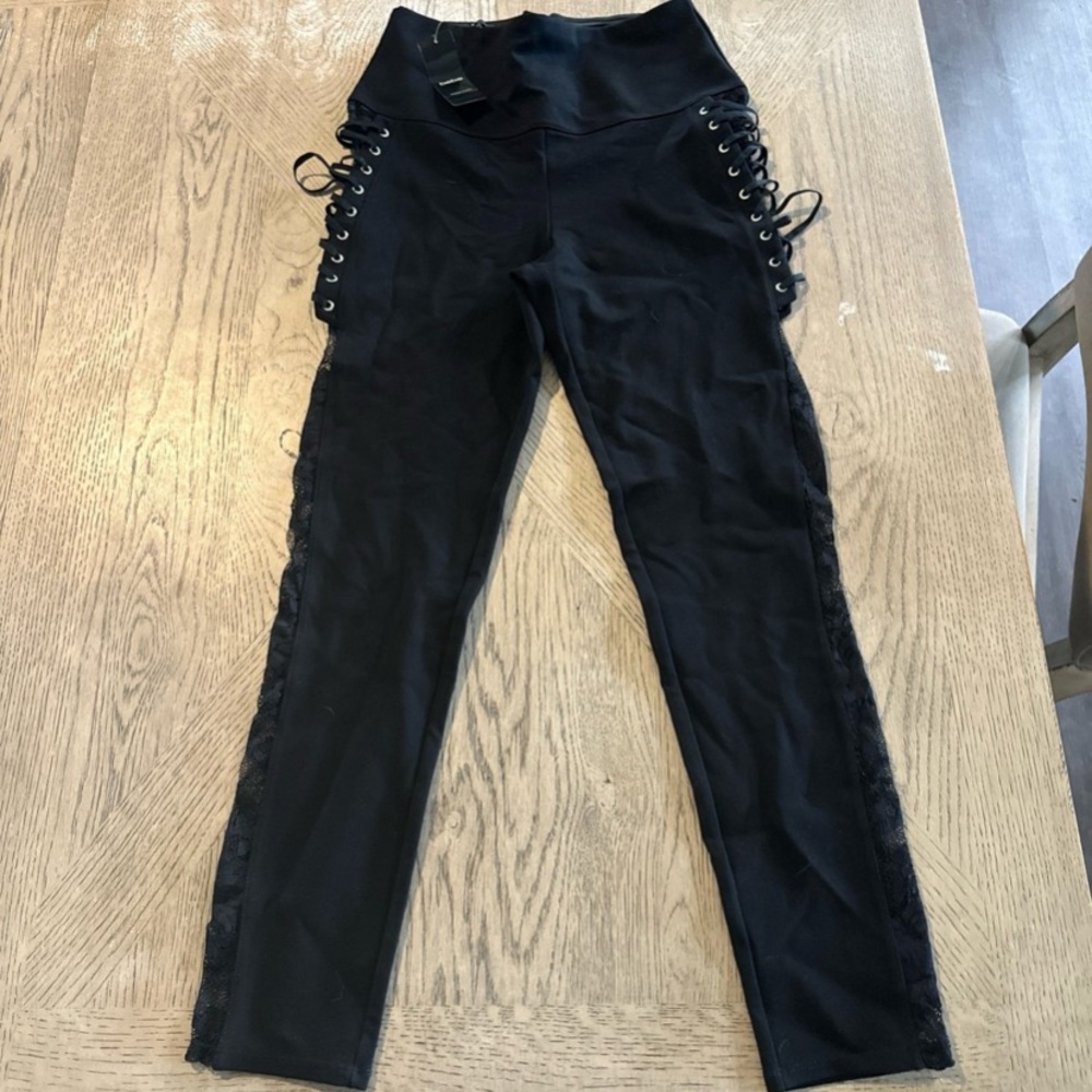Bebe black fancy leggings with zipper, crisscross & lace detailing on the sides.